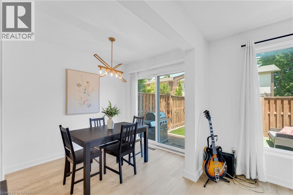 Dining space with wood-finish flooring and a contemporary linear chandelier - 5275 Banting Court, Burlington, ON