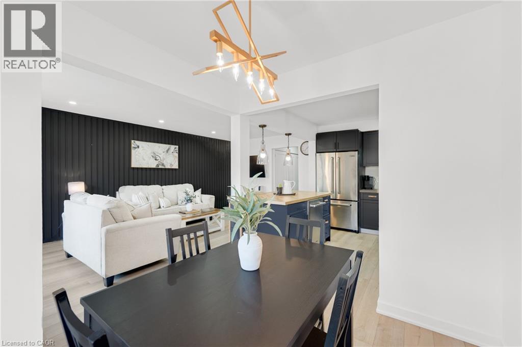 Spacious dining area featuring a dark wood-finish table and an abstract linear chandelier - 5275 Banting Court, Burlington, ON