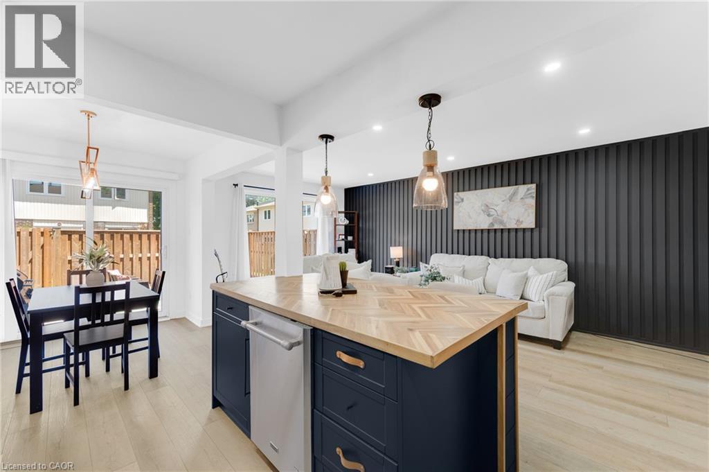 Kitchen island with a herringbone wood-finish countertop, dark blue cabinetry, and integrated dishwasher - 5275 Banting Court, Burlington, ON