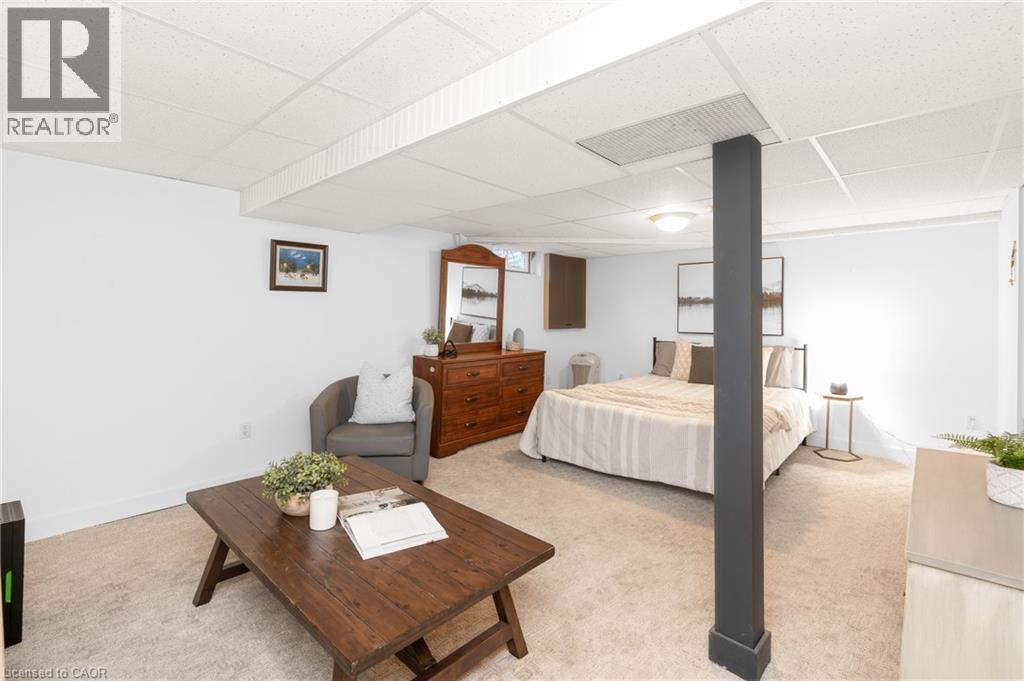 Carpeted room with a drop ceiling, white walls, and a dark support pillar - 5275 Banting Court, Burlington, ON
