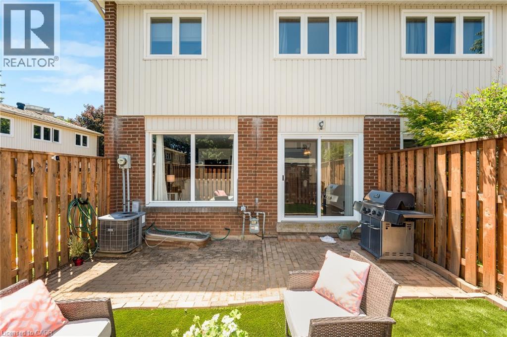 Private rear patio featuring a brick paver surface and a partial fence - 5275 Banting Court, Burlington, ON
