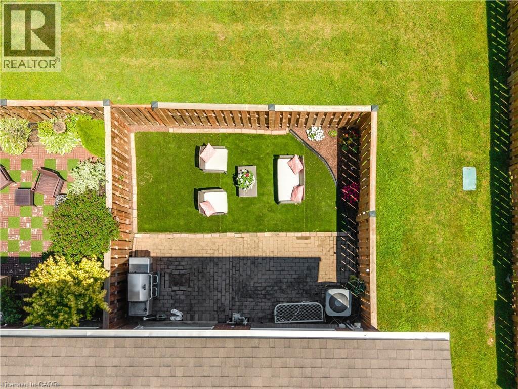 Fenced backyard featuring a brick paver patio, a separate artificial turf area, and established plantings - 5275 Banting Court, Burlington, ON