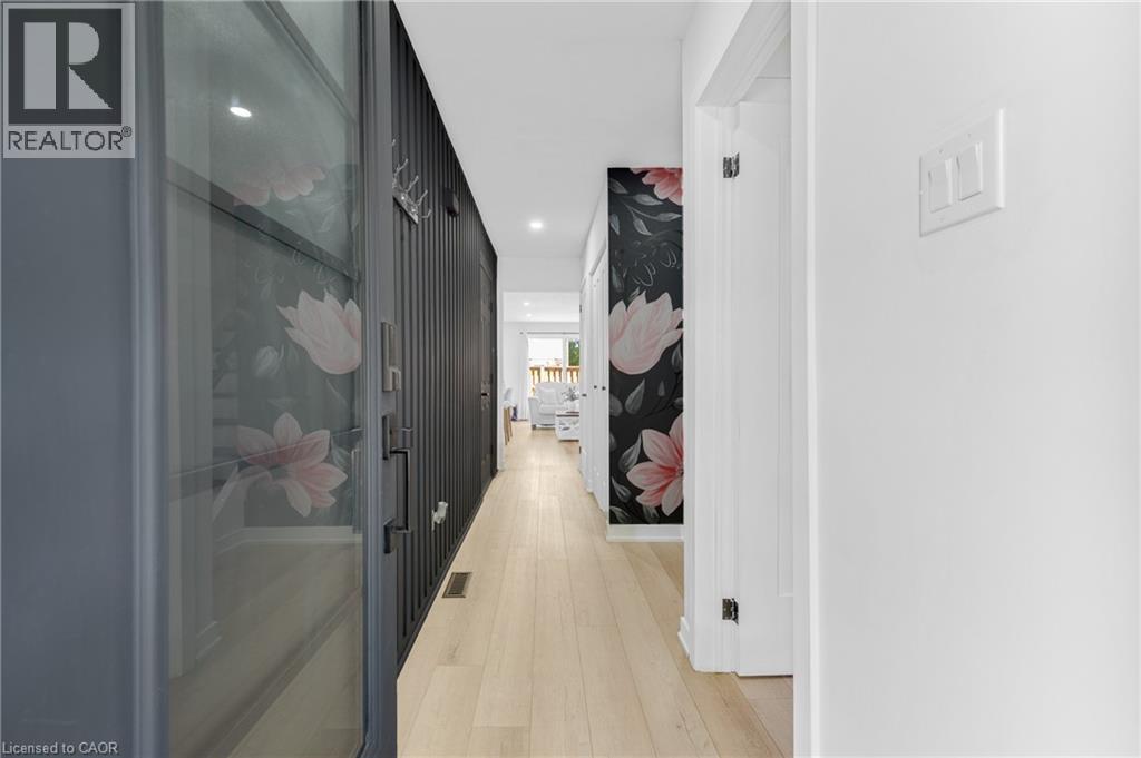 Contemporary hallway featuring light wood-finish flooring, recessed lighting, and a prominent decorative accent wall - 5275 Banting Court, Burlington, ON