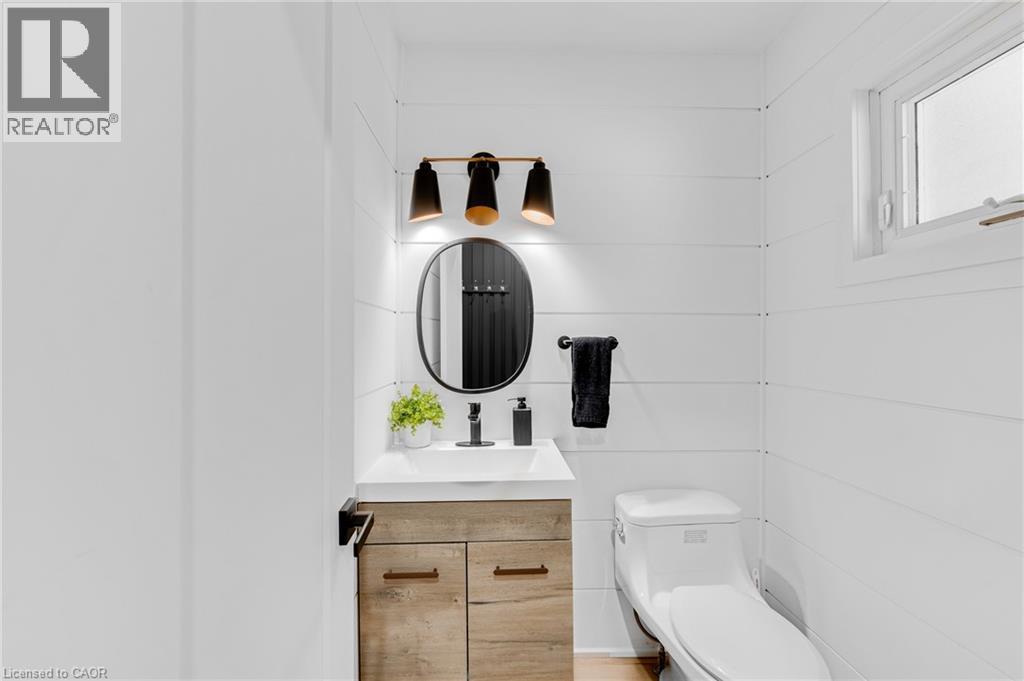Modern bathroom featuring white shiplap walls and a natural wood-finish vanity with a white countertop - 5275 Banting Court, Burlington, ON