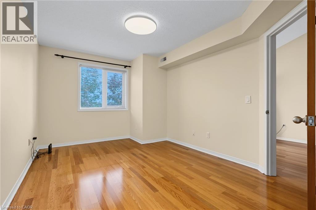 Hardwood flooring throughout featuring a window with white trim, a flush mount ceiling light fixture, and a solid wood interior door - 117 E Bristol Road E Unit# 64, Mississauga, ON