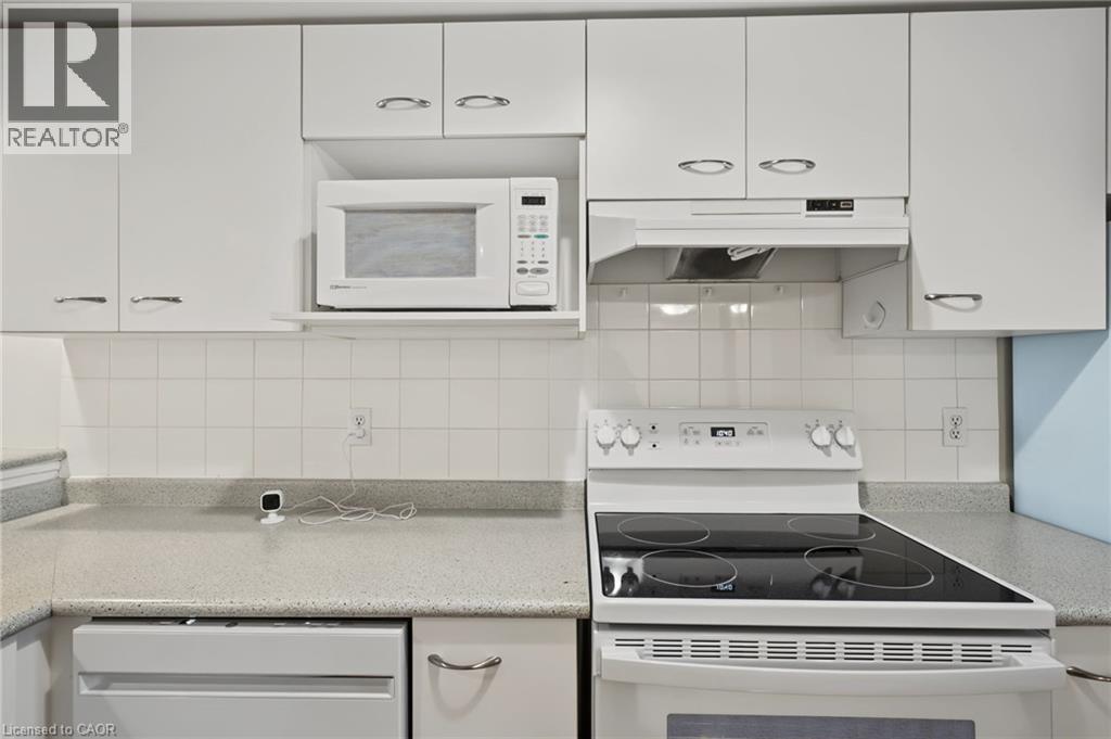 Kitchen featuring white cabinetry with silver-tone hardware, a tiled backsplash, and light-toned countertops - 117 E Bristol Road E Unit# 64, Mississauga, ON