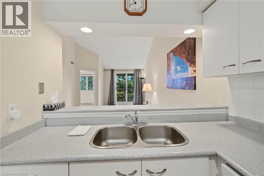 Kitchen pass-through featuring a double basin stainless steel sink and light-toned speckled countertops - 117 E Bristol Road E Unit# 64, Mississauga, ON