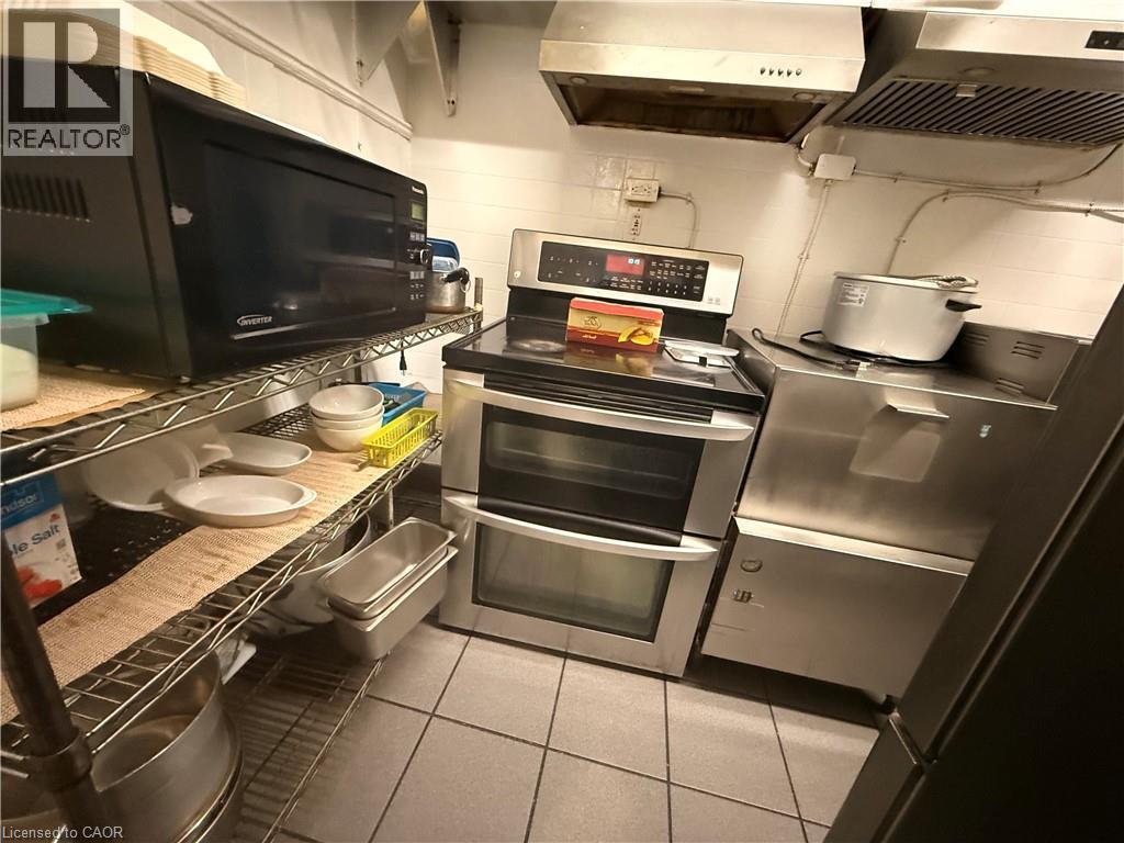Functional kitchen space featuring a stainless steel double oven range, stainless steel vent hoods, and industrial-style wire shelving - 486 James Street N, Hamilton, ON