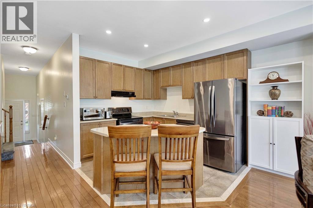 Kitchen featuring wood-finish cabinetry, stainless steel appliances, and an eat-in island with seating - 120 Beddoe Drive Unit# 6, Hamilton, ON