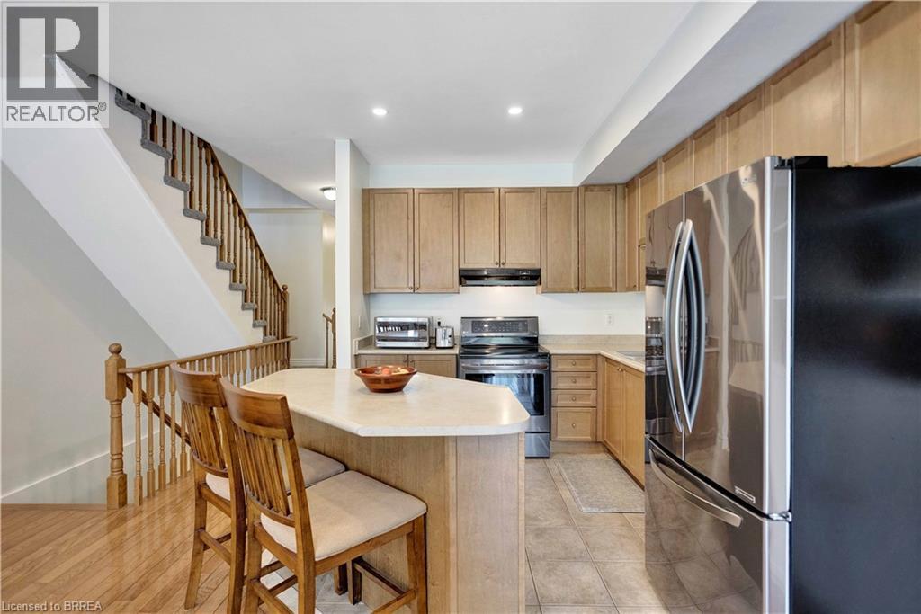 Kitchen featuring wood-finish cabinetry, stainless steel appliances, and an eat-in island with seating - 120 Beddoe Drive Unit# 6, Hamilton, ON