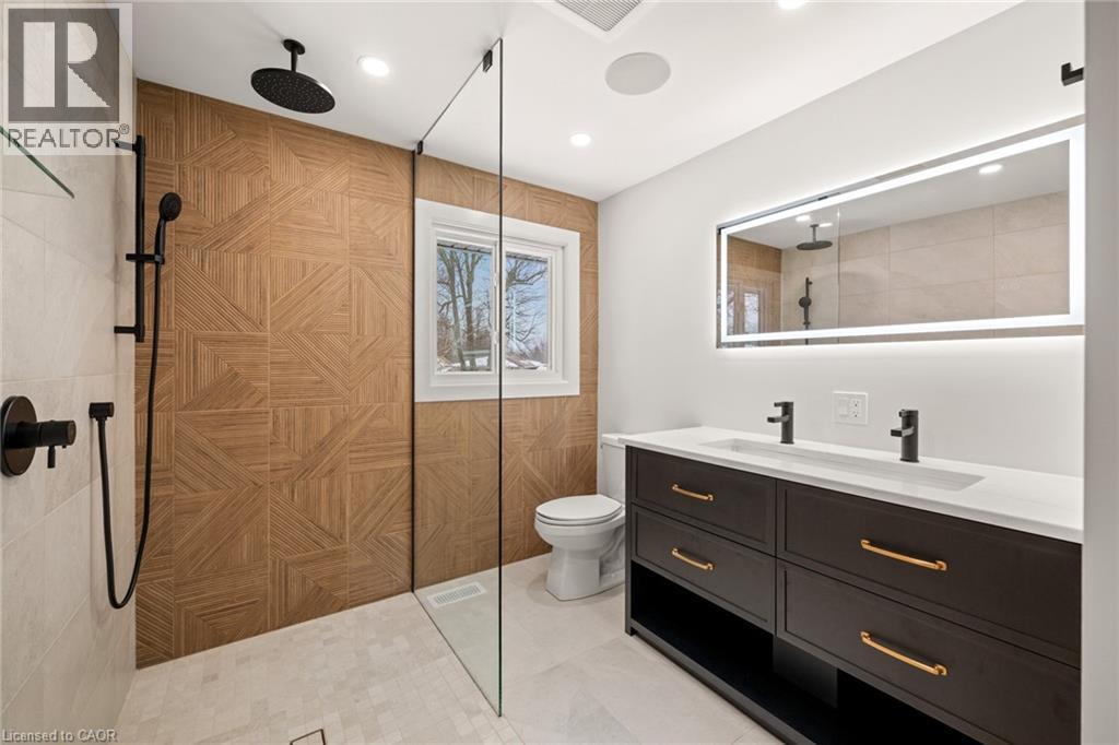 Contemporary bathroom featuring a walk-in shower with patterned wood-finish wall tile and matte black fixtures - 361 Coleridge Place, Waterloo, ON - Indoor Photo Showing Bathroom