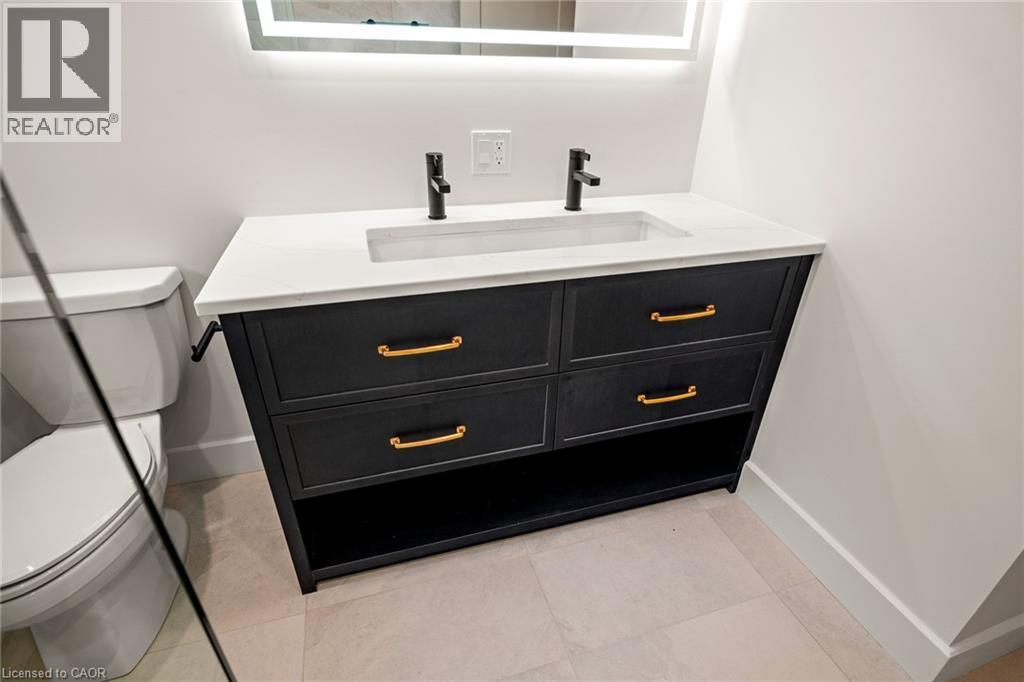 Bathroom vanity featuring a quartz countertop with an integrated sink, matte black faucets, and an illuminated mirror - 361 Coleridge Place, Waterloo, ON - Indoor