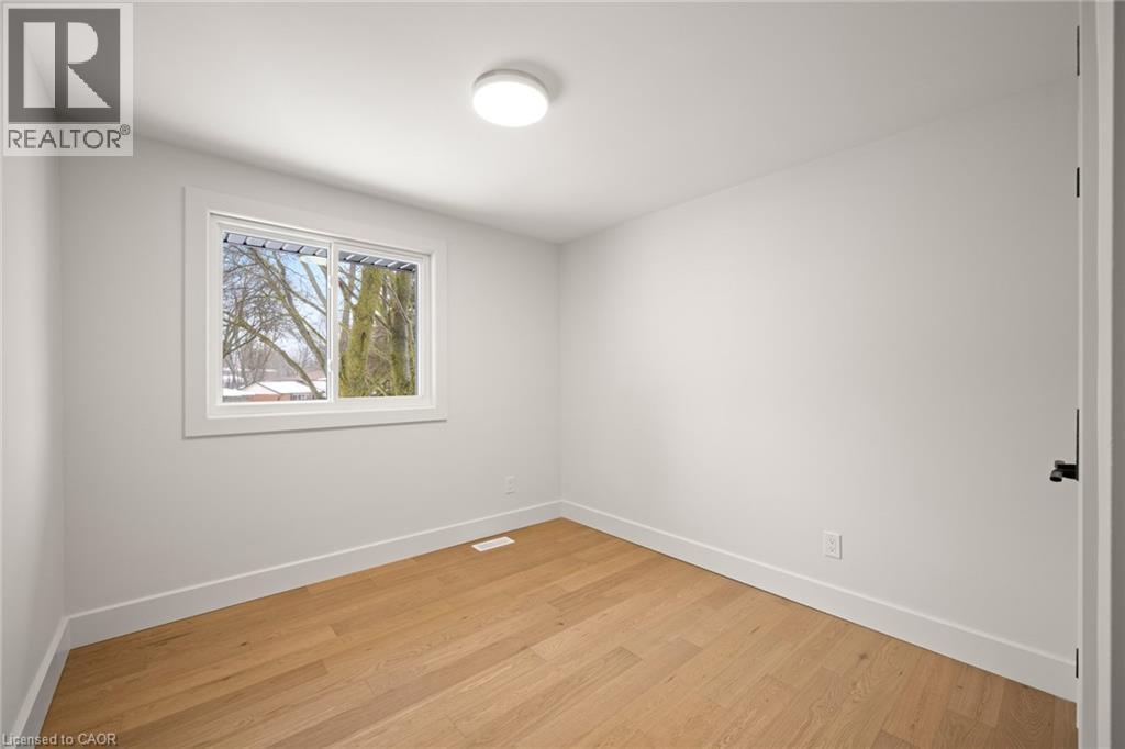 Bright interior space featuring a window with white trim, wood-finish flooring, white walls, and a ceiling-mounted light fixture - 361 Coleridge Place, Waterloo, ON - Indoor Photo Showing Other Room
