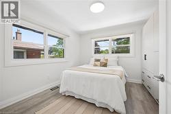Light-filled interior featuring two windows with white trim, wood-finish flooring, a contemporary flush-mount ceiling light, and custom built-in cabinetry with black hardware -