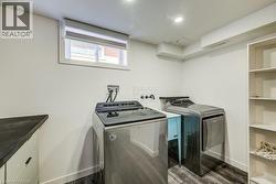 Dedicated laundry area featuring a utility sink, dark wood-finish flooring, and recessed lighting -
