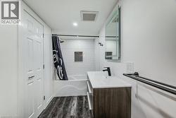 Contemporary bathroom featuring a white subway tile shower, built-in shower niche, dark wood-finish vanity with an integrated sink, and dark wood-finish flooring -