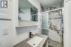 Modern bathroom featuring a walk-in shower with large format marble-look tile and a sliding glass door -
