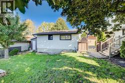 Expansive grassy backyard featuring a multi-level wood deck with railings, a wood privacy fence, and mature trees -