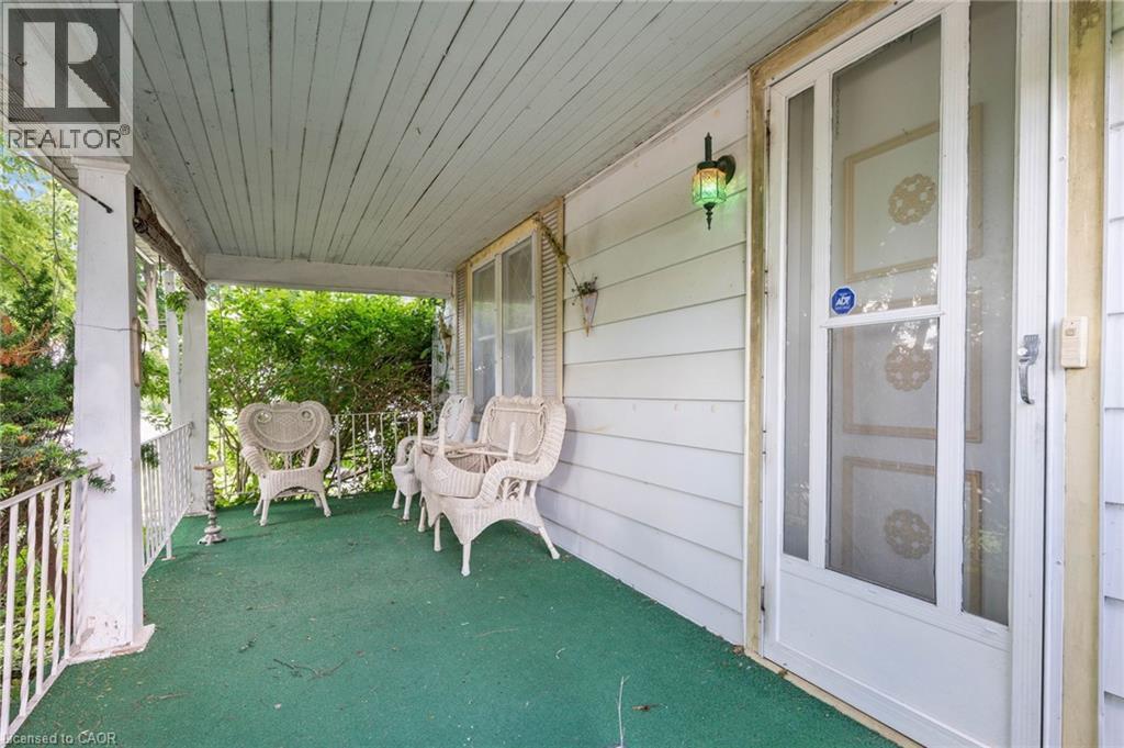 Covered front porch featuring white siding and a green outdoor carpet - 35 Basil Avenue, Simcoe, ON