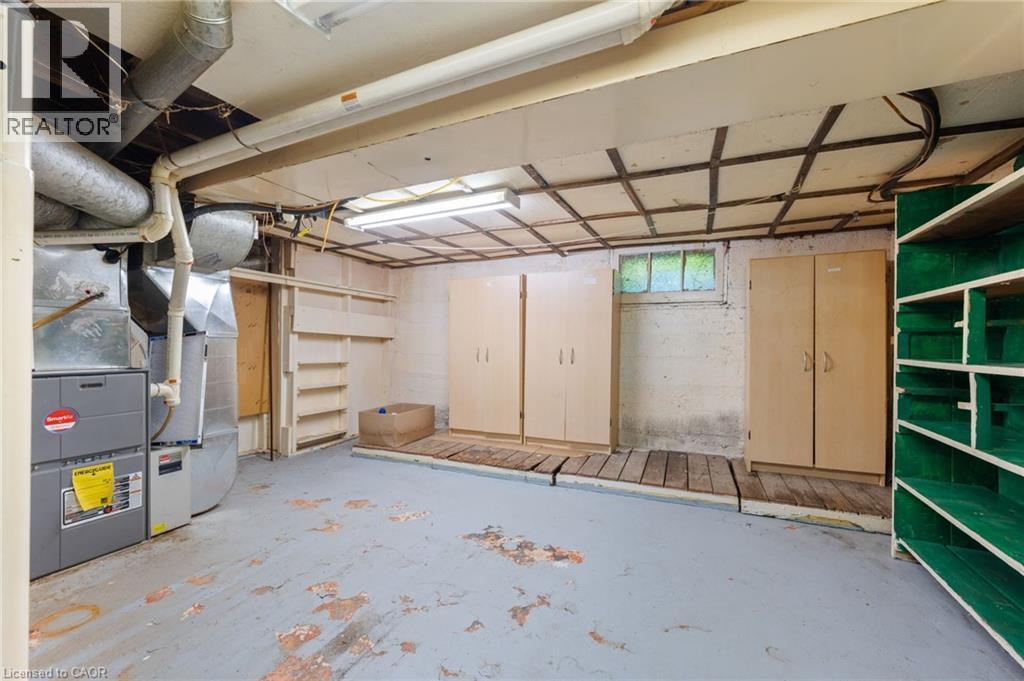 Utility room featuring a furnace system, exposed ductwork, built-in shelving, two standalone storage cabinets, and a window providing natural light - 35 Basil Avenue, Simcoe, ON