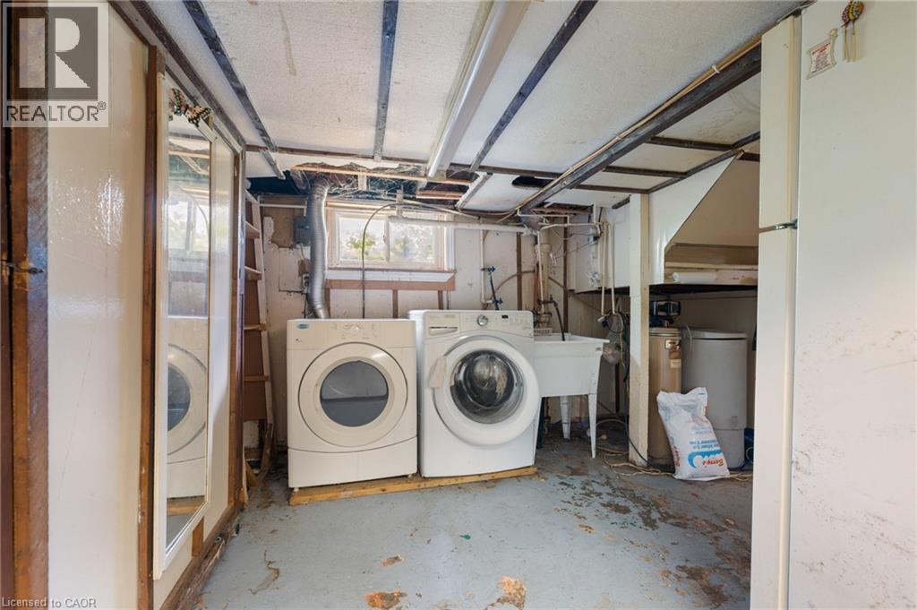 Basement utility area featuring a washer and dryer, a utility sink, and exposed ceiling joists - 35 Basil Avenue, Simcoe, ON