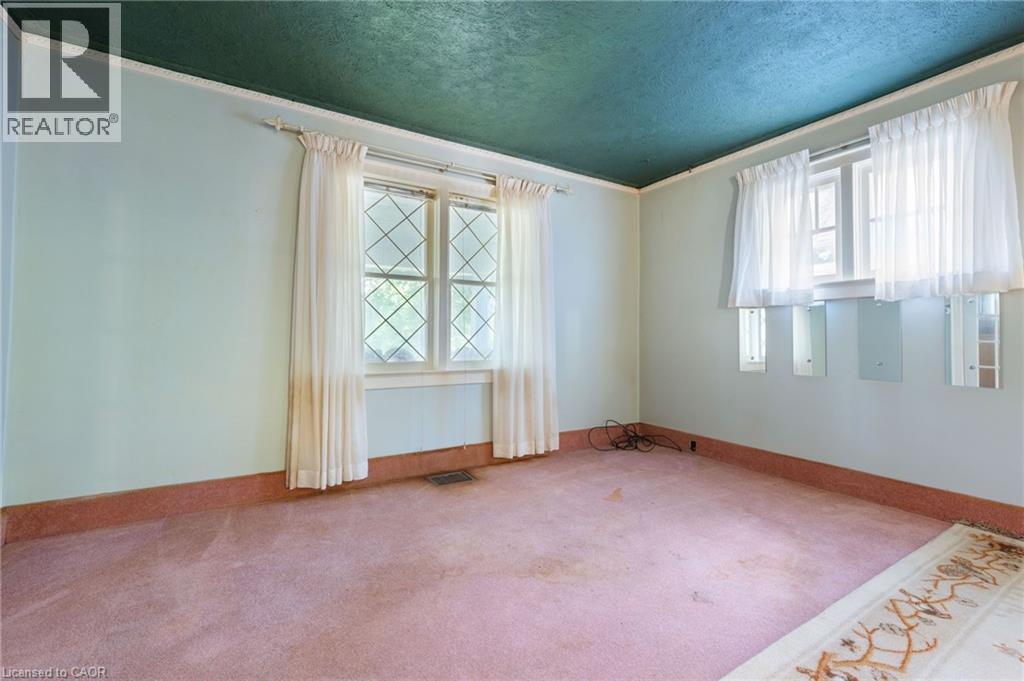Room featuring a diamond-pane window, light blue walls, a textured green ceiling, and pink carpeting - 35 Basil Avenue, Simcoe, ON