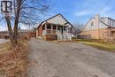 Brick and siding home featuring a covered front porch with white railings, a gravel driveway, and a chain-link fence - 880 Lawrence Road, Hamilton, ON 
