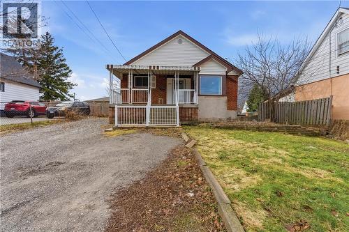 Brick and siding exterior featuring a covered front porch with white railings, and a prominent front-facing window - 880 Lawrence Road, Hamilton, ON 