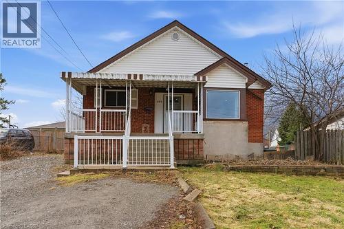 Brick and siding exterior featuring a covered front porch with white railings, a front-facing gable, a bay window, and a gravel driveway - 880 Lawrence Road, Hamilton, ON 