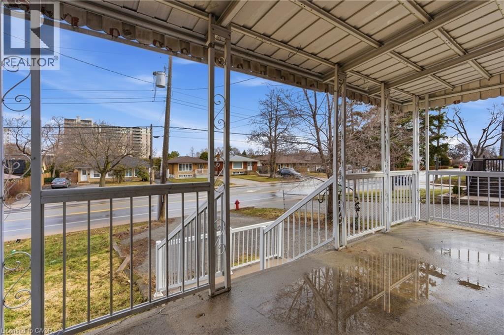 Covered front porch with white metal railings, ornamental scrollwork accents, and a concrete floor - 880 Lawrence Road, Hamilton, ON