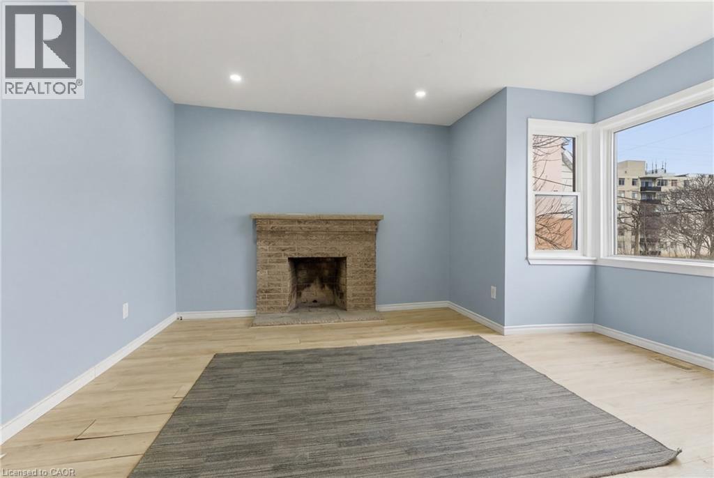Living area with a stone fireplace, recessed ceiling lighting, and light wood-finish flooring - 880 Lawrence Road, Hamilton, ON