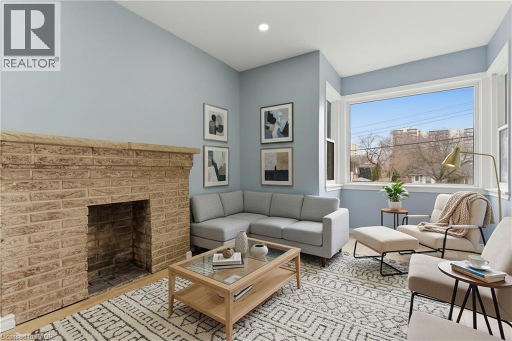 Living area featuring a stone-clad fireplace and light wood-finish flooring - 880 Lawrence Road, Hamilton, ON