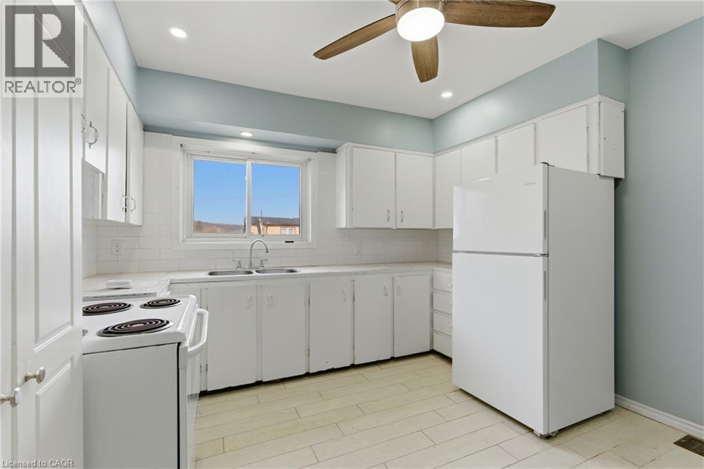 Kitchen featuring white cabinetry, subway tile backsplash, light-toned flooring, and a ceiling fan with integrated lighting - 880 Lawrence Road, Hamilton, ON
