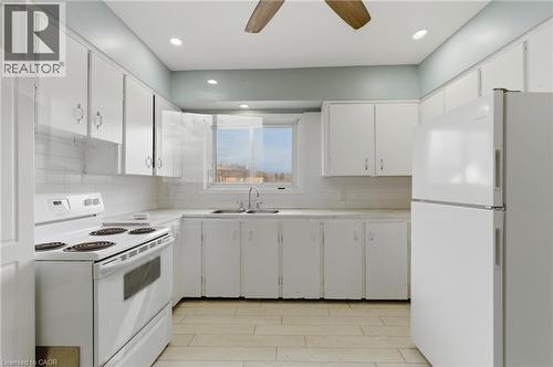Kitchen featuring white cabinetry, white appliance suite, white subway tile backsplash, light-toned countertops, and wood-finish flooring - 880 Lawrence Road, Hamilton, ON 