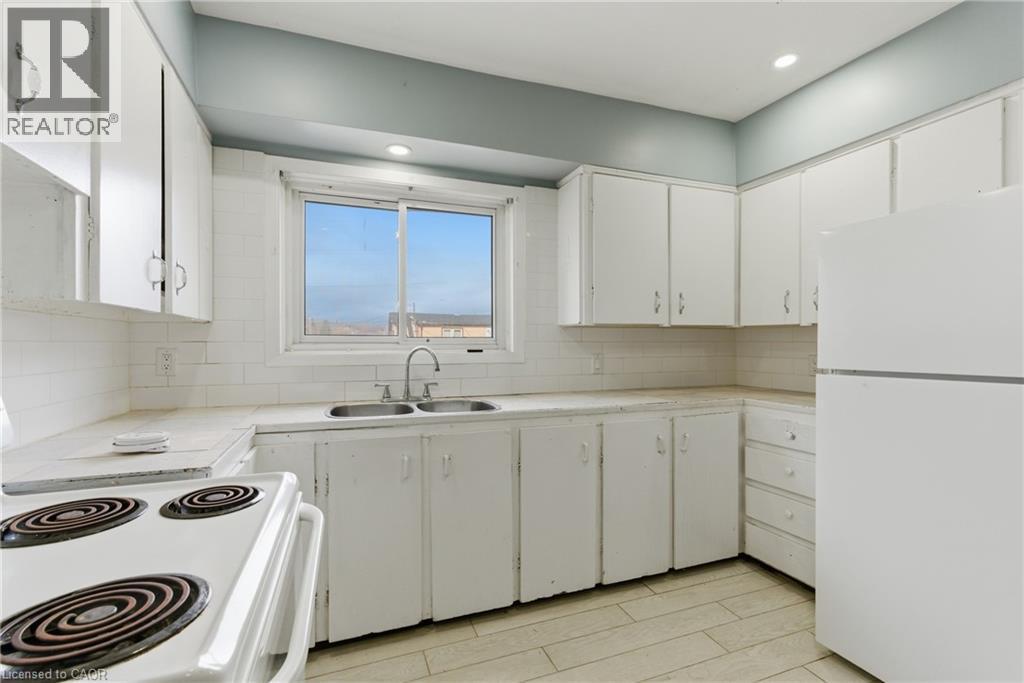 Kitchen featuring white cabinetry, a double basin sink with chrome faucet, and white tile flooring - 880 Lawrence Road, Hamilton, ON