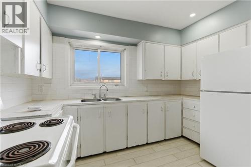 Kitchen featuring white cabinetry, a double basin sink with chrome faucet, and white tile flooring - 880 Lawrence Road, Hamilton, ON 