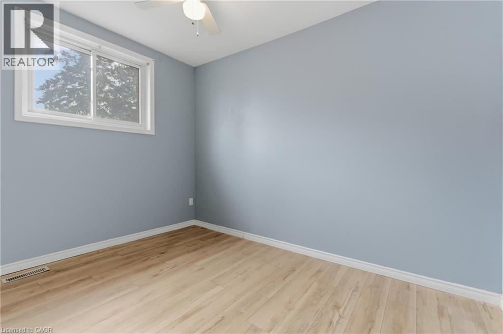 Room featuring light blue walls, wood-finish flooring, and white trim - 880 Lawrence Road, Hamilton, ON