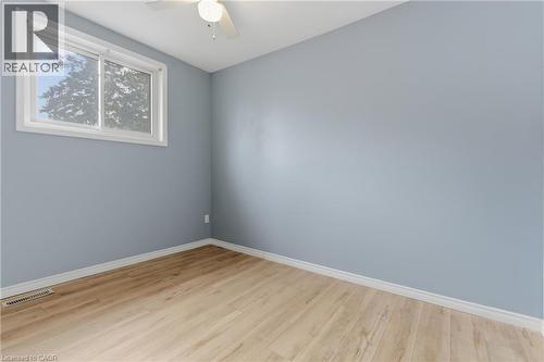 Room featuring light blue walls, wood-finish flooring, and white trim - 880 Lawrence Road, Hamilton, ON 