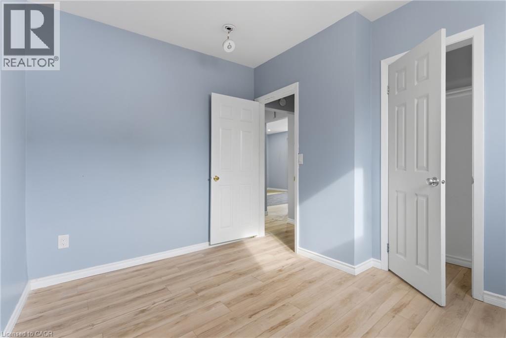 Interior room featuring light blue walls, white trim, and wood-finish flooring - 880 Lawrence Road, Hamilton, ON