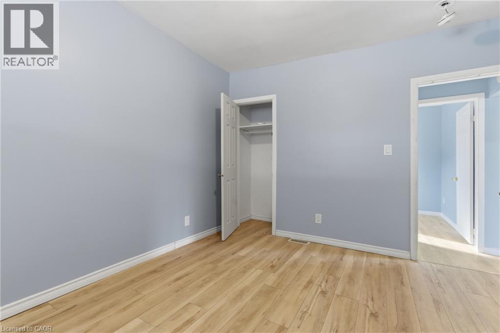 Room featuring wood-finish flooring, light blue walls, white trim, and a closet with bifold doors - 880 Lawrence Road, Hamilton, ON