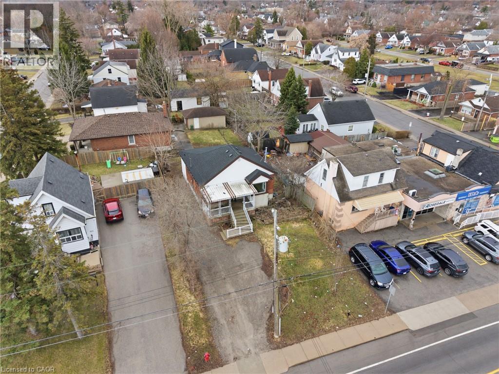 Aerial perspective showcasing a residential property with a dark shingle roof and light-colored siding, positioned among other residential and commercial buildings - 880 Lawrence Road, Hamilton, ON
