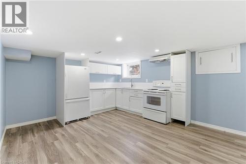 Kitchen space featuring wood-finish flooring, white cabinetry, integrated appliances, recessed lighting, and a window - 880 Lawrence Road, Hamilton, ON 