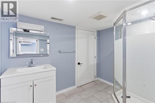 Bathroom featuring a white vanity with integrated sink, chrome faucet, and a rectangular mirror - 880 Lawrence Road, Hamilton, ON 