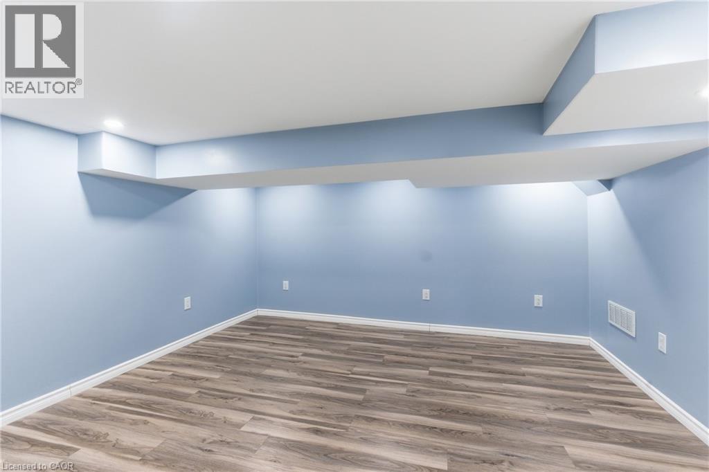 Finished lower level with wood-finish flooring, light blue walls, recessed lighting, and white baseboards - 880 Lawrence Road, Hamilton, ON