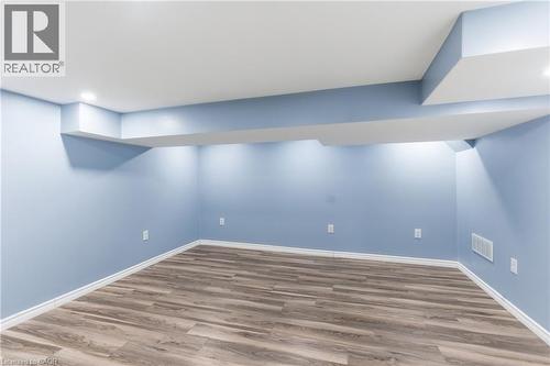 Finished lower level with wood-finish flooring, light blue walls, recessed lighting, and white baseboards - 880 Lawrence Road, Hamilton, ON 