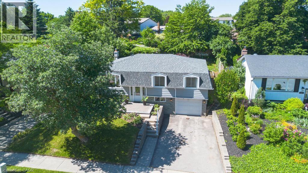 Dormer-style residence featuring a gray facade, integrated garage, and a long concrete driveway - 14 Gateway Drive, Guelph, ON