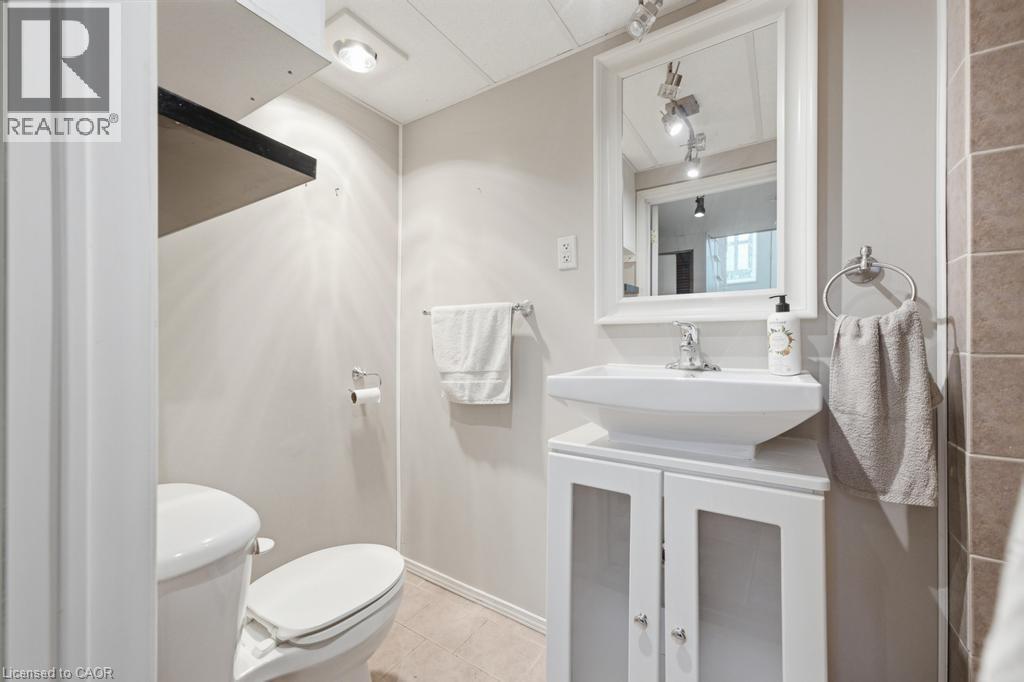 Bathroom featuring a white rectangular vessel sink atop a white vanity with clear-paneled doors, a framed mirror, and chrome fixtures - 14 Gateway Drive, Guelph, ON