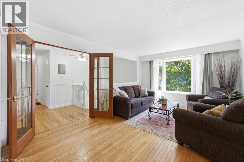 Living area featuring wood-finish flooring, a large picture window with ample natural light, and classic French doors - 14 Gateway Drive, Guelph, ON