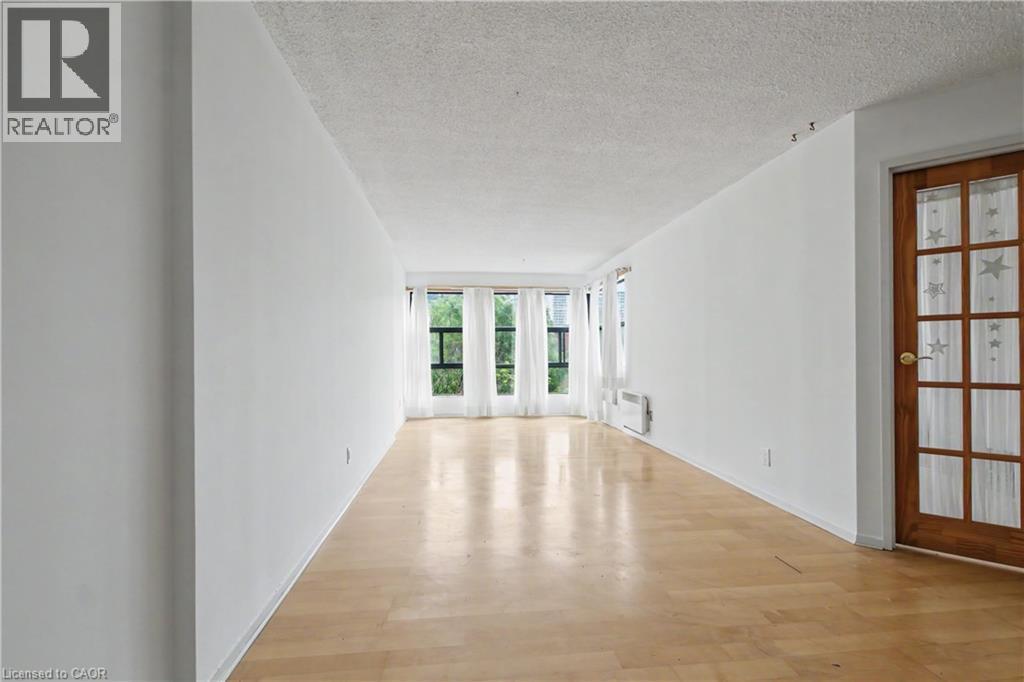 Bright interior space featuring wood-finish flooring, white walls, and a textured ceiling - 175 Hunter Street E Unit# 401, Hamilton, ON - Indoor Photo Showing Other Room