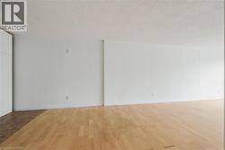 Spacious interior featuring light wood-finish flooring, white painted walls, and an acoustic ceiling finish -